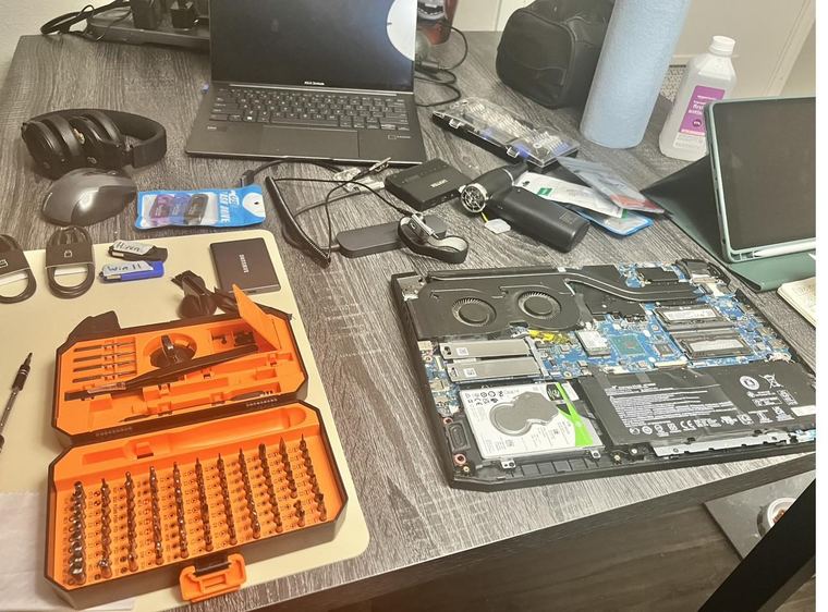Laptop opened to the motherboard beside a full tool kit