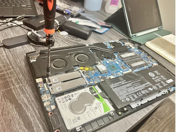 Laptop internals with twin fans, heat pipes, an M.2 SSD, a 1TB drive and the battery visible